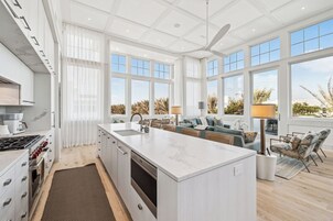 Cozinha moderna com uma ilha grande, eletrodomésticos embutidos e janelas amplas com vista para o exterior.