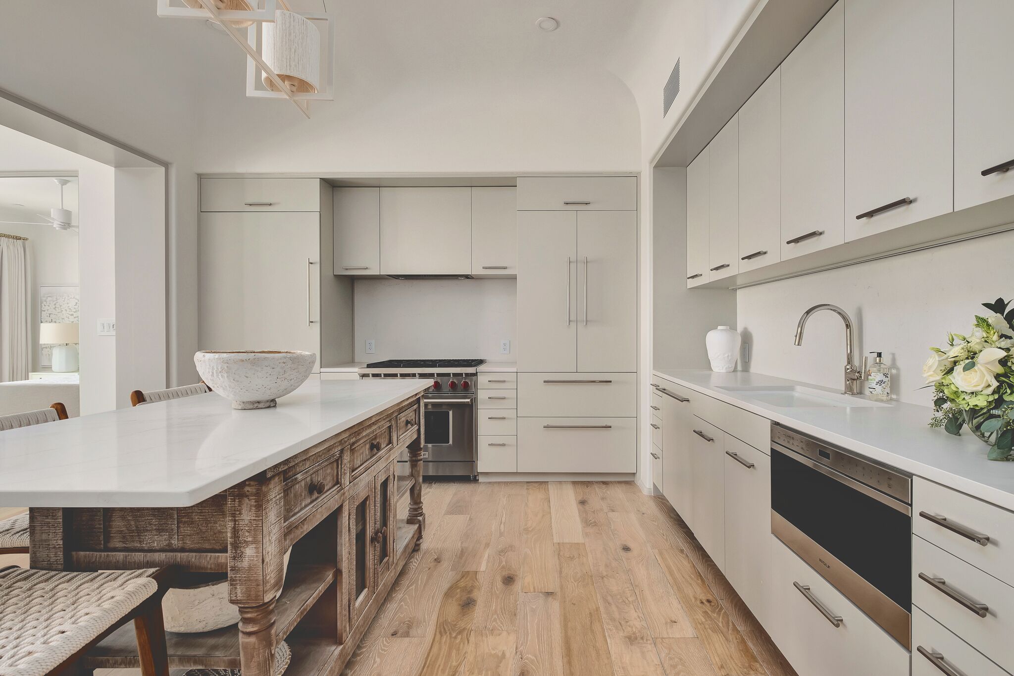 Una cocina moderna con una isla grande, mesa de comedor de madera y electrodomésticos integrados.