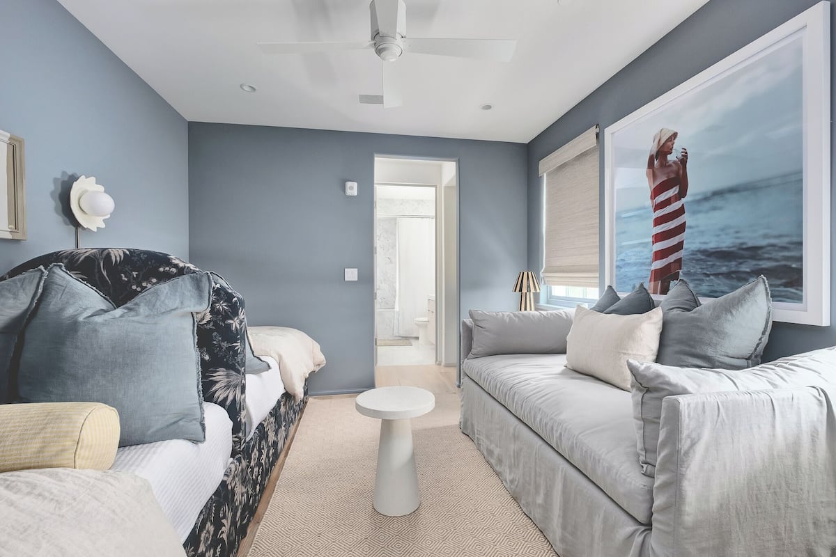 Una sala moderna con un sofá gris, un sillón estampado y una mesa de centro redonda.