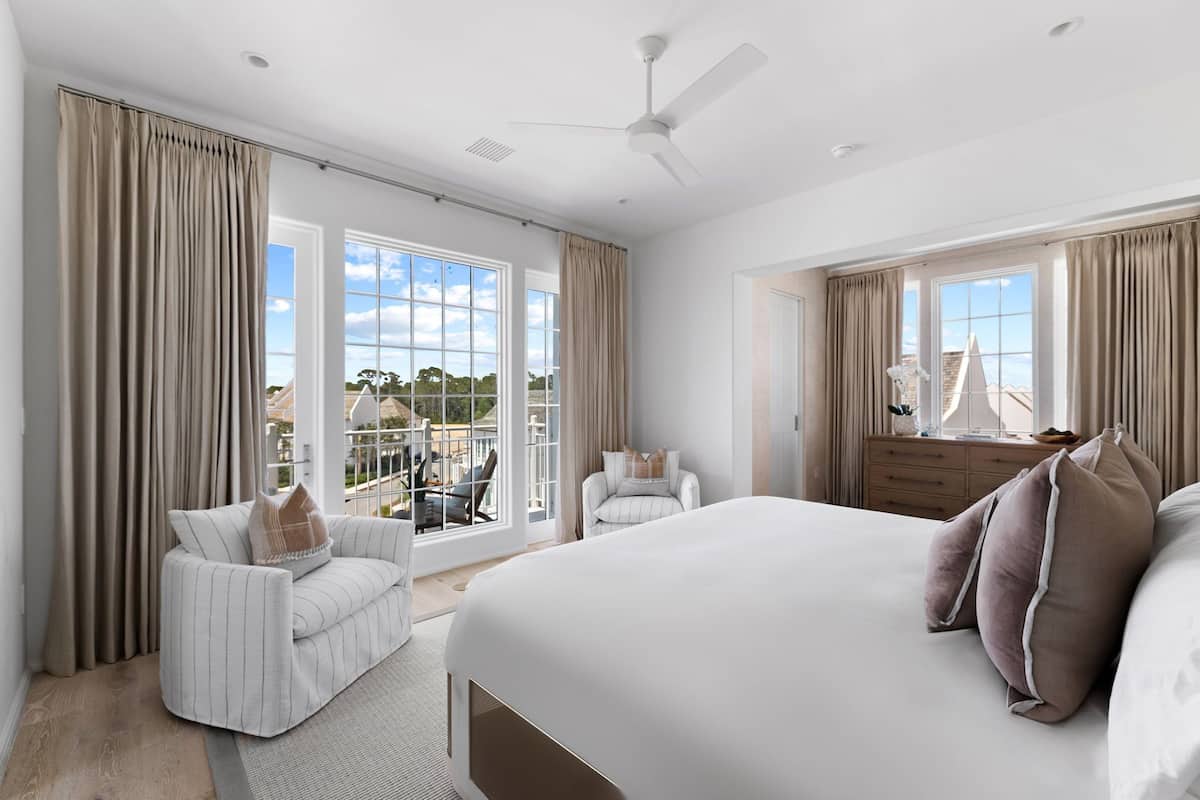 Un dormitorio amplio con una cama grande, una zona de estar con una silla y un balcón con vistas.