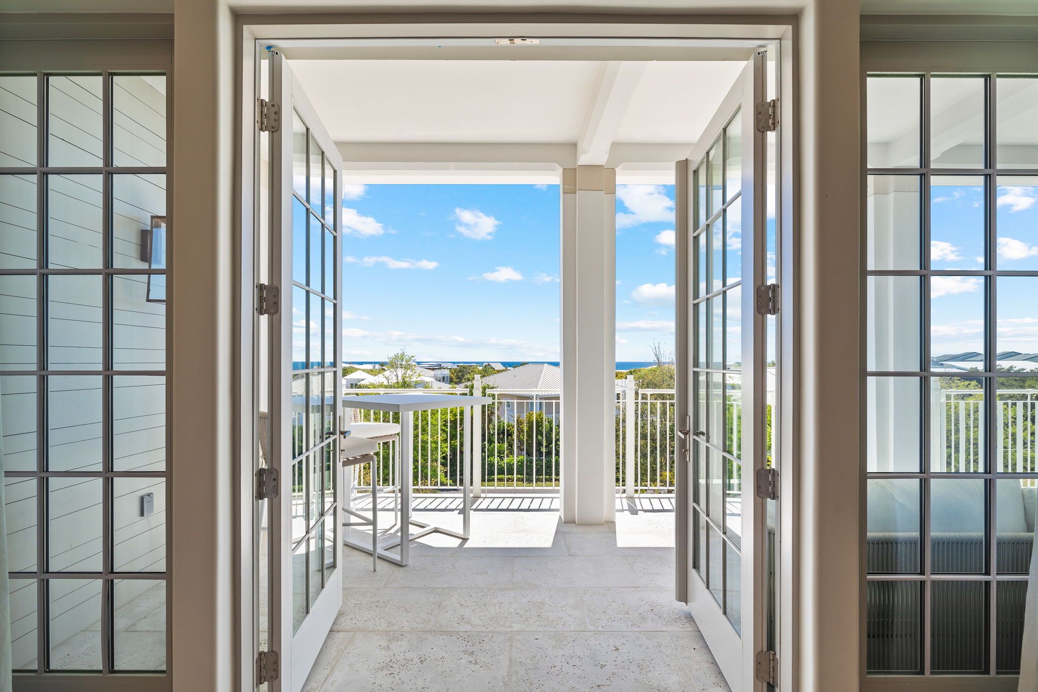 A balcony with a table and chairs, a view of the sky, and a distant landscape.