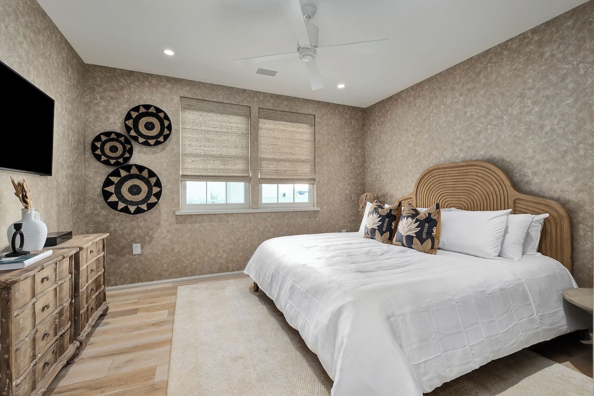Un dormitorio con cama, cabecera de madera, decoración en la pared y televisión.