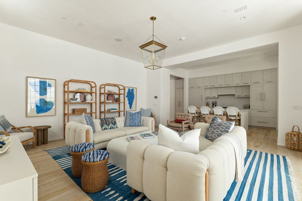 Una sala de estar moderna con un conjunto de sofás, un comedor y una cocina al fondo.