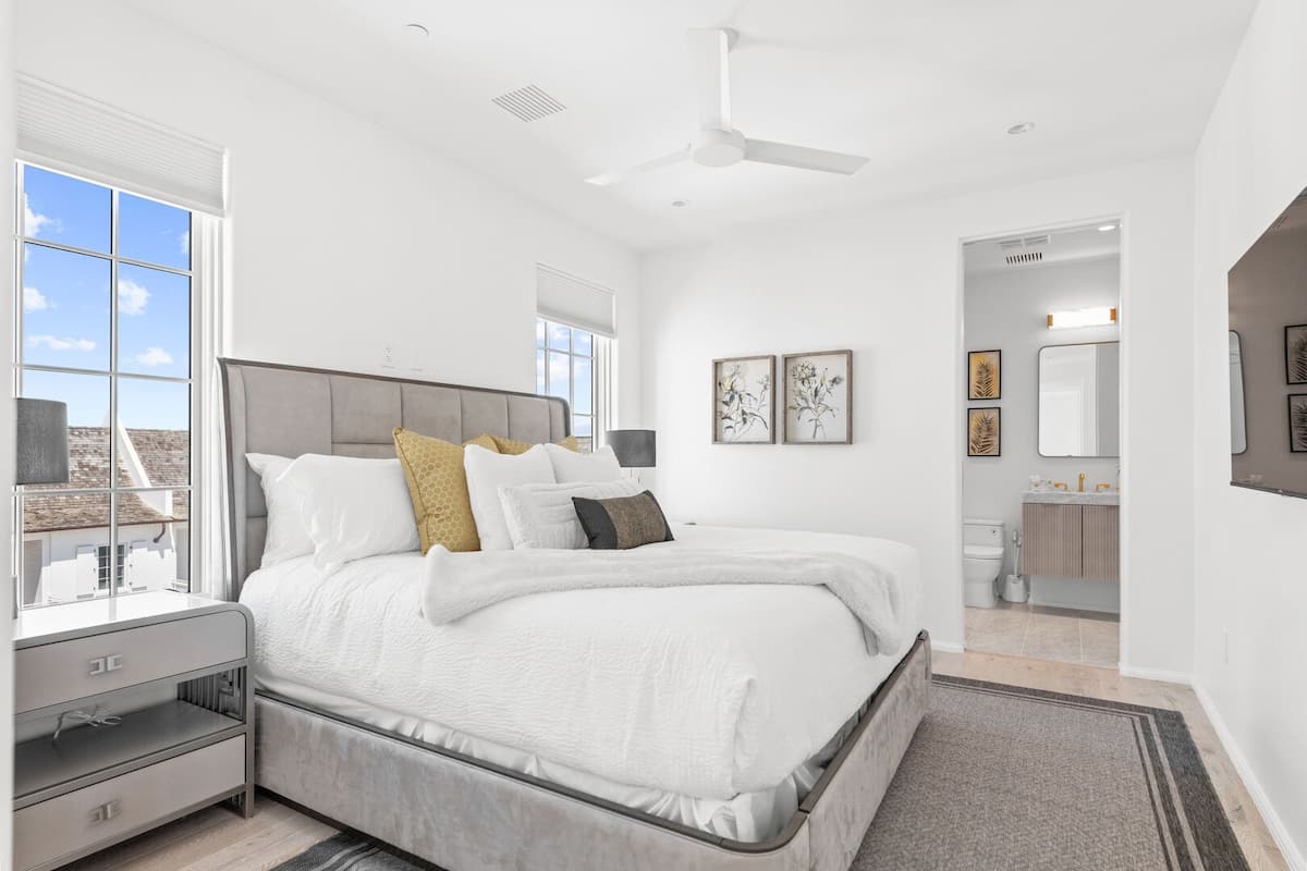 Un dormitorio moderno con una cama grande, una mesita de noche, un aparador y vistas al exterior.