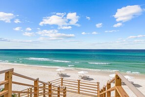 A wooden deck leading to a beach with white umbrellas and lounge chairs. - Kaiya Beach Resort (Panama City Beach)