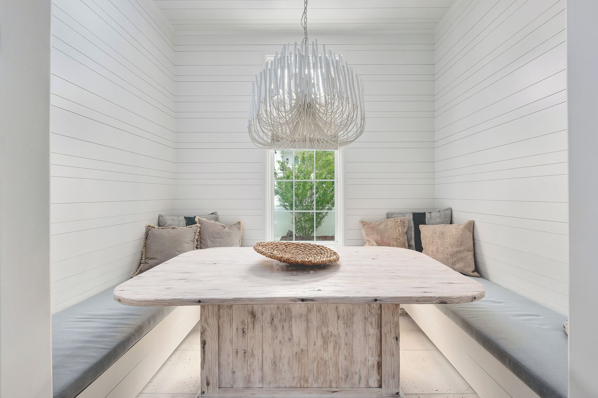 Et rum med et centralt træbord, bænke og en hængende lampe.