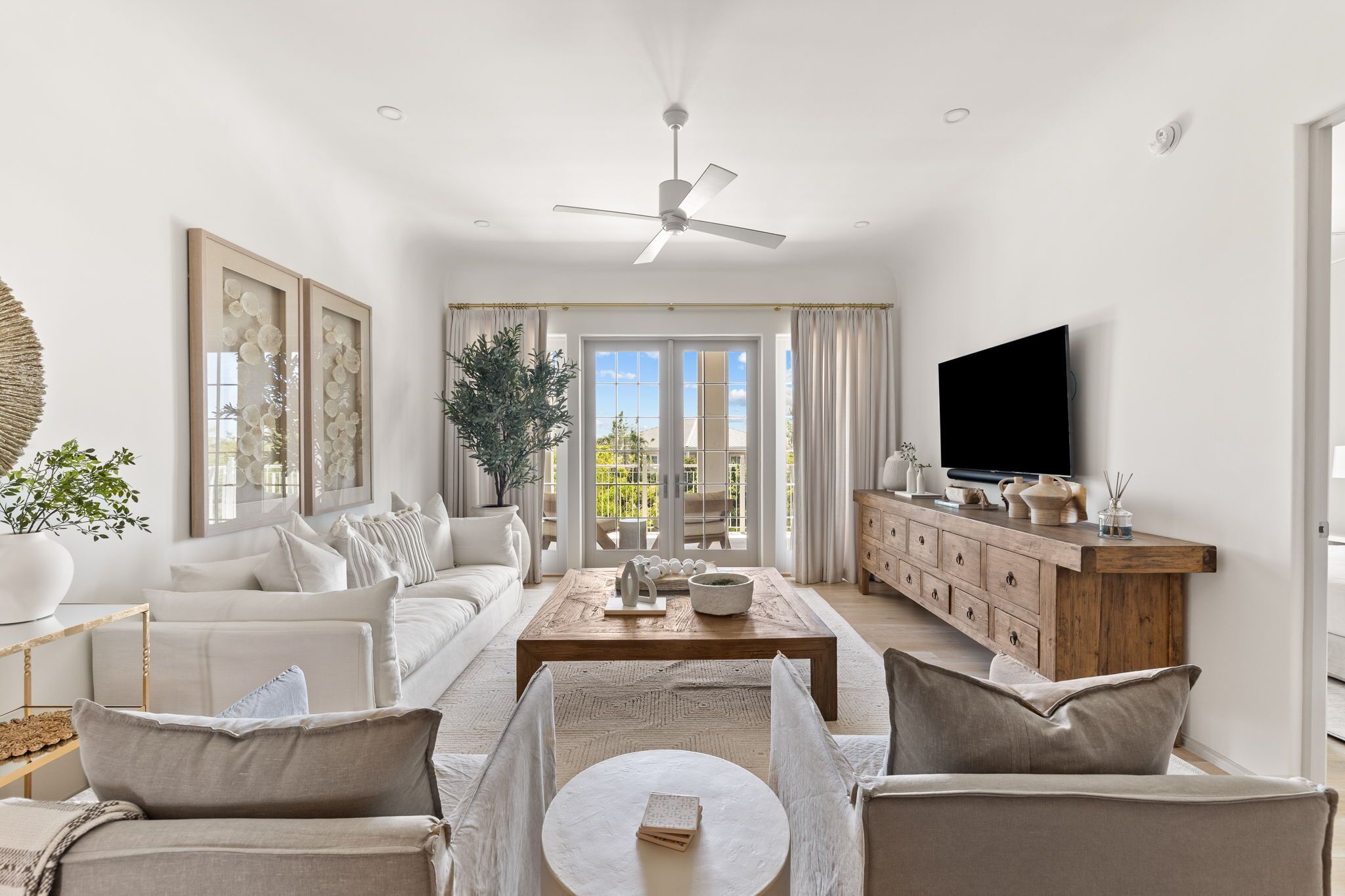 A spacious living room with a large sofa, a coffee table, a TV, and a wooden cabinet.