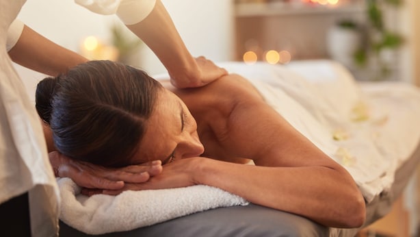 A person receiving a massage in a room with a bed, a white towel, and a shelf with items in the background. - La Perla del Caribe  (Riohacha)