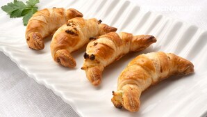 Four golden-brown croissants on a white plate with a parsley garnish. - La Perla del Caribe  (Riohacha)