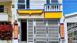 A two-story building with a white facade, blue roof, and yellow accents on the entrance. - La Perla del Caribe  (Riohacha)