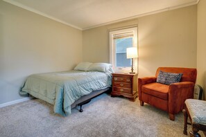 A bedroom with a bed, a nightstand, a chair, and a window.