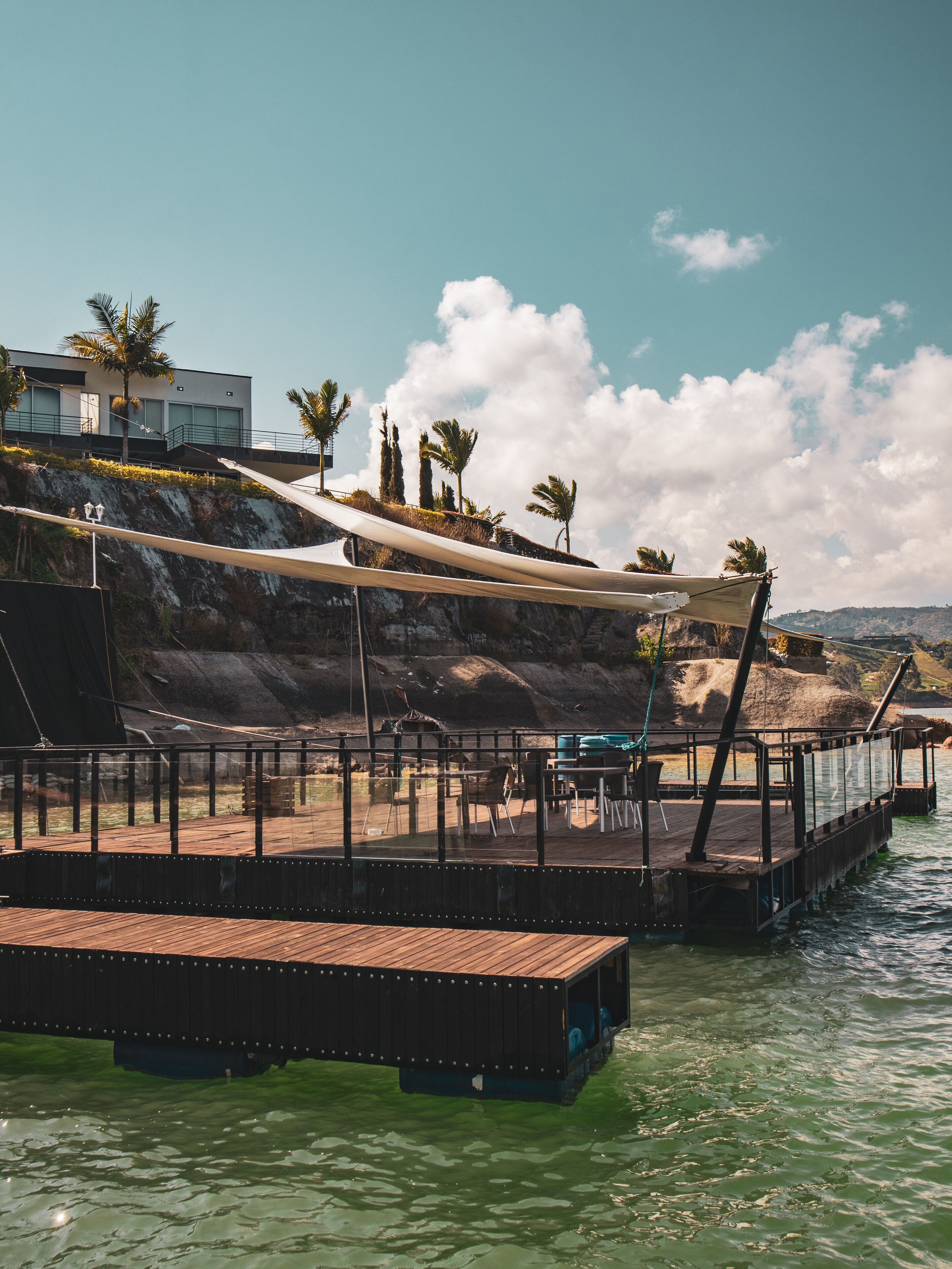 A waterfront deck with a wooden floor, metal railing, and a canopy.