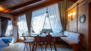 A wooden interior with a dining table, chairs, and a bench. - Elegant Ampezzo-style apartment with breathtaking views of the Dolomites. (Cortina d'Ampezzo)