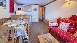 Ein gemütliches Wohnzimmer mit einem roten Sofa und einer Essecke mit einem Holztisch, gedeckt für eine Mahlzeit.