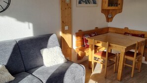 A cozy room with a grey sofa, wooden dining table, and chairs. - Ski-in/ski-out & foot of the slopes, 5th floor, view ski slopes, balcony, tv, ski locker, 23m² (La Plagne)