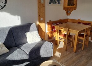 A cozy room with a grey sofa, wooden dining table, and chairs. - Ski-in/ski-out & foot of the slopes, 5th floor, view ski slopes, balcony, tv, ski locker, 23m² (La Plagne)
