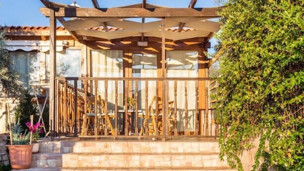 A wooden pergola structure with a stone staircase leading up to a covered area.