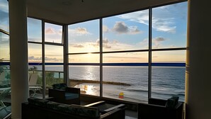 A room with large windows overlooking a body of water, a pool, and a sunset. - Aparatamentos con vista al mar Palmetto1 (Cartagena)