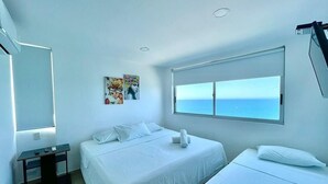 A hotel room with two beds, a large window with a view of the sea, a small table with a lamp, and a painting on the wall. - Aparatamentos con vista al mar Palmetto1 (Cartagena)