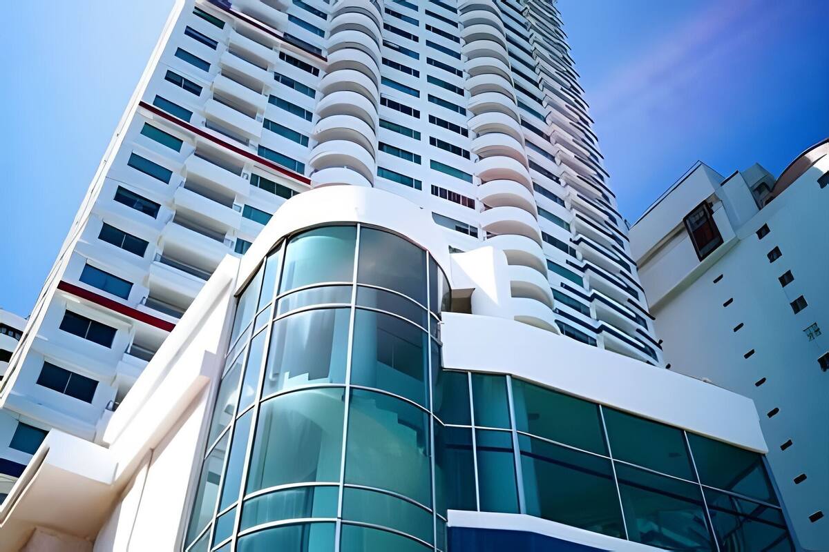 A modern high-rise building with a curved glass facade and multiple balconies.