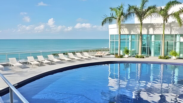 A poolside area with lounge chairs and a view of the ocean. - Aparatamentos con vista al mar Palmetto1 (Cartagena)