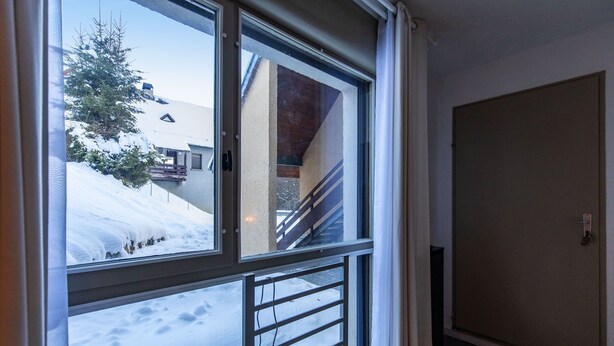 A room with a large window overlooking a snowy landscape, a door, and a staircase leading to an upper level. - Le Bastan - Appt pour 4 avec Jardin (Barèges)