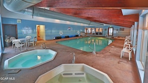 A pool area with two pools, a hot tub, and seating. - Spacious 3Bed condo 5 min from Winter Park, walk 2 Town & steps from bus stop! (Winter Park)