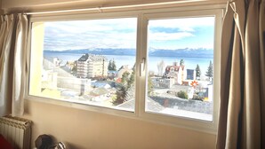A room with a large window offering a view of a lake and mountains. - Apartments Bariloche - Downtown, Mitre (San Carlos de Bariloche)