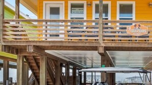 A yellow building with a wooden deck and a sign for 'Tequila Sunrise'.