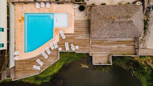 An aerial view of a swimming pool area with wooden deck and lounge chairs.