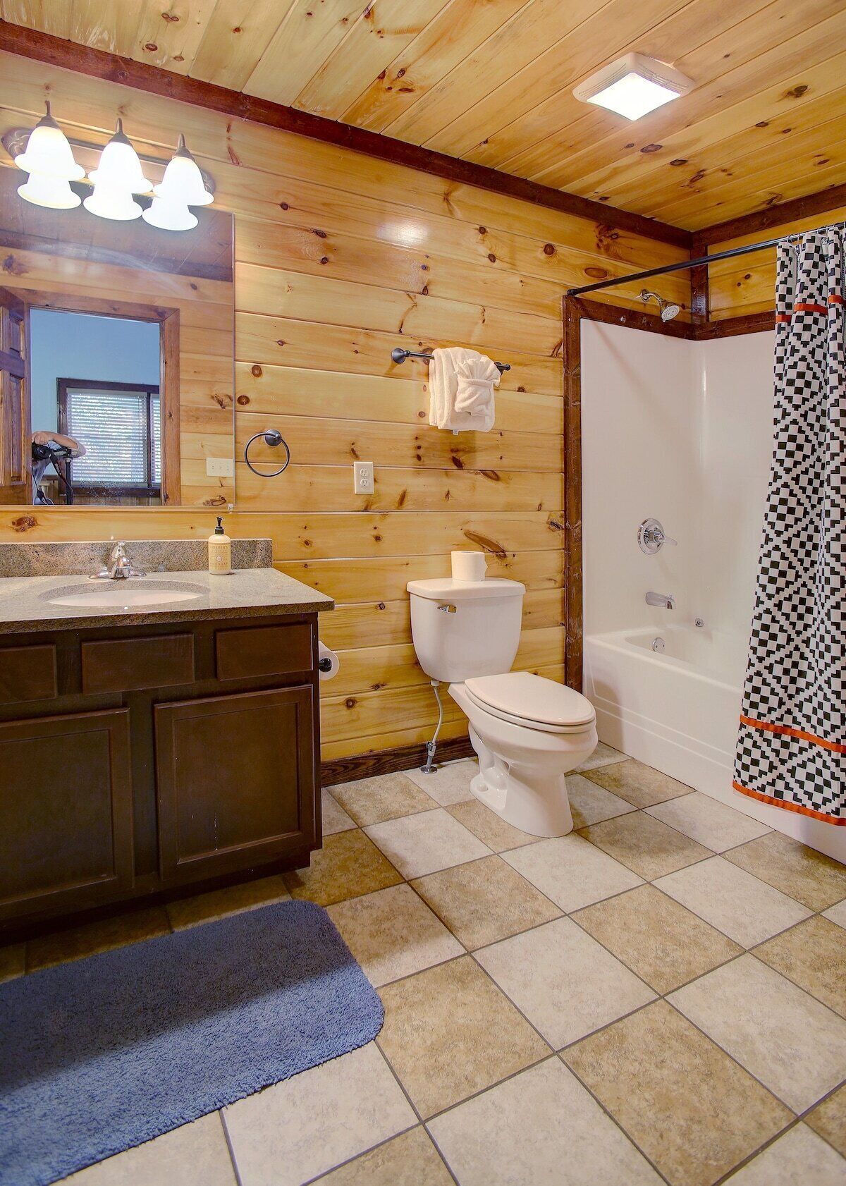 A wooden cabin bathroom with a sink, toilet, and shower.