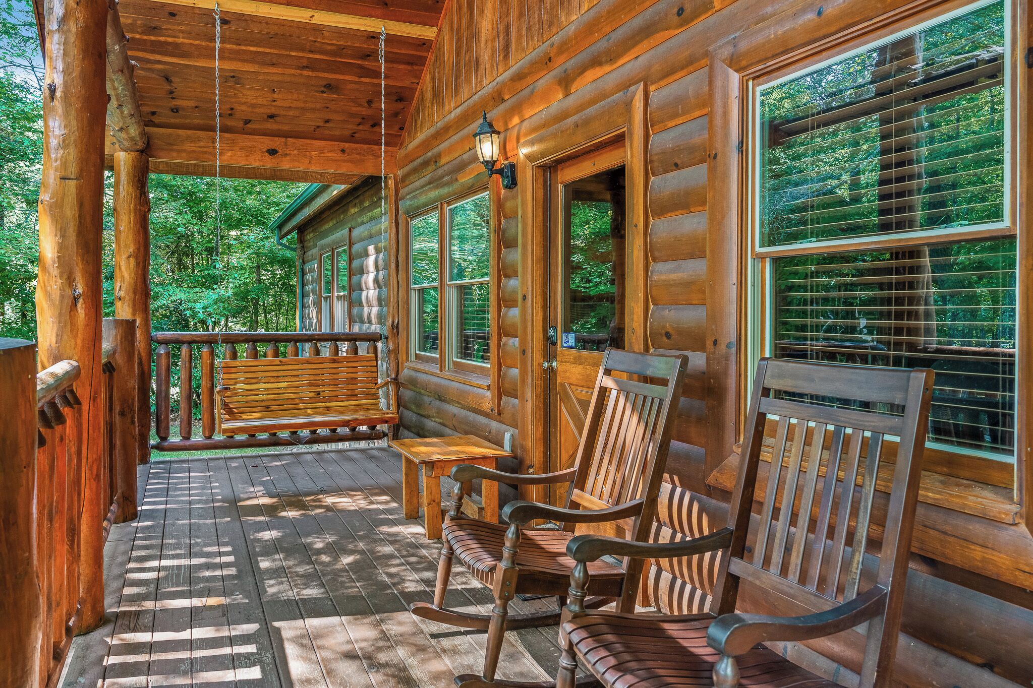 Une cabane en bois avec une véranda, des fauteuils à bascule et une table.