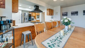 Une cuisine moderne dotée d’un îlot central, de chaises en bois et d’une table à manger agrémentée d’un chemin de table à motifs floraux.