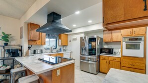 Une cuisine moderne avec des meubles en bois, des appareils électroménagers en acier inoxydable et un plan de travail en marbre.