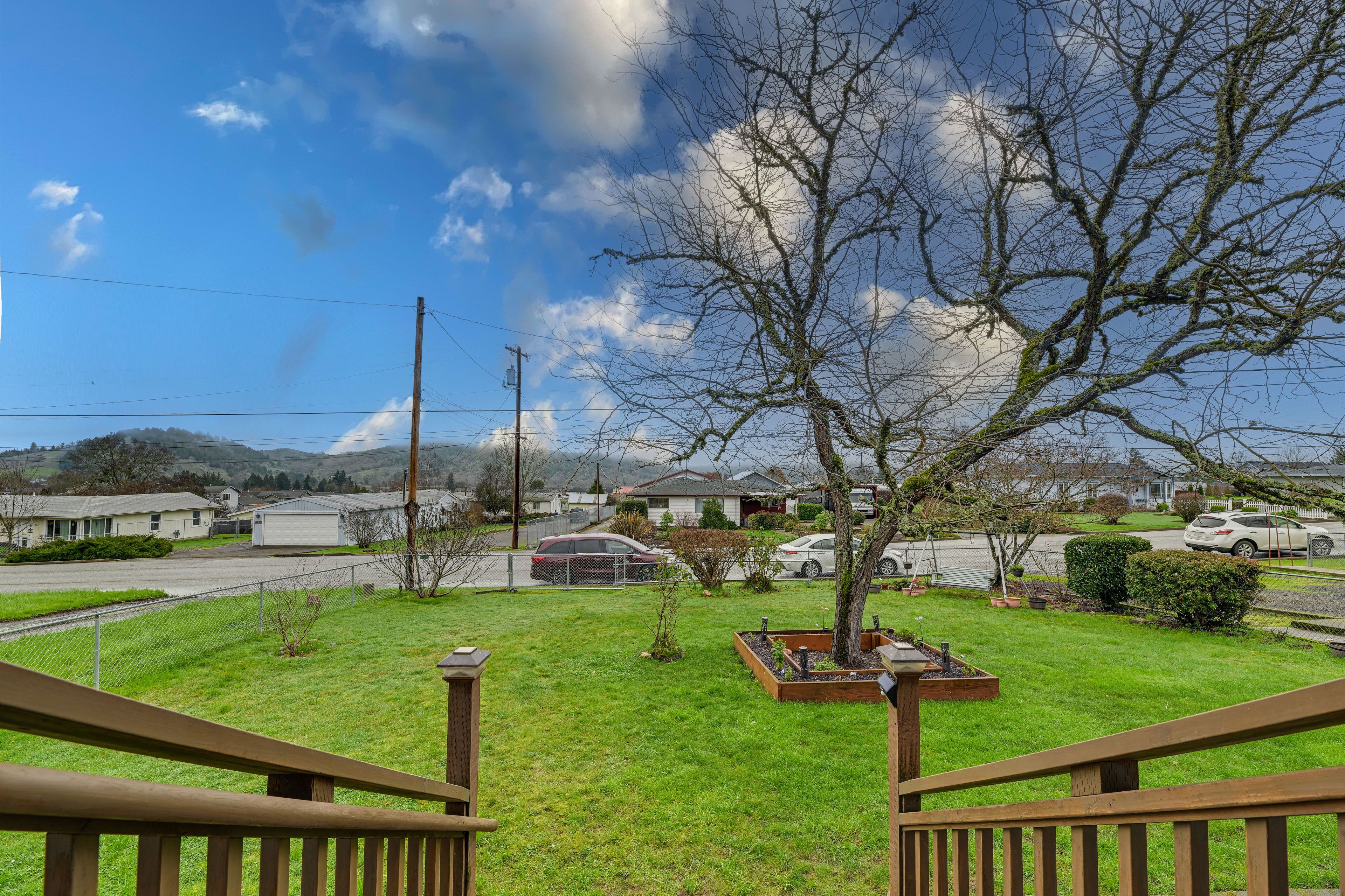 Un barrio residencial con césped, una terraza de madera y casas al fondo.