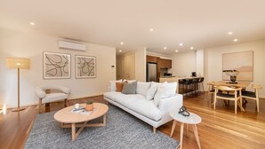 A modern living room with a sofa, coffee table, and a dining area with chairs and a table.