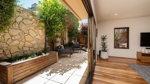 A modern living room with a stone wall, wooden bench, and potted plants.