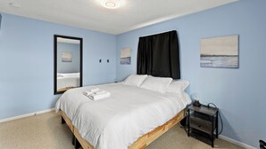 A bedroom with a bed, a nightstand, a mirror, and two paintings on the wall.