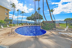 A swimming pool with lounge chairs, palm trees, and a view of the ocean. - New Luxury Oceanfront Condo ★ Amazing 180° Ocean Views ★ Top-Floor Corner-Unit (Wailuku)