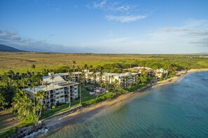 An aerial view of a beachfront hotel with multiple buildings, a sandy beach, and a clear view of the ocean. - New Luxury Oceanfront Condo ★ Amazing 180° Ocean Views ★ Top-Floor Corner-Unit (Wailuku)