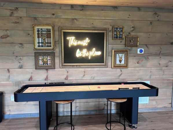 A pool table with a neon sign that reads "This is the place" in a room with wooden walls and framed pictures. - Luxury 3-story cabin! MTN Views Hot Tub, Game Room, Fire Pit, Book Fall Now! (Gatlinburg)