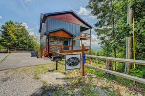 A lodge with a stone facade, wooden deck, and a sign indicating it is part of the Woodland Reserve. - Luxury 3-story cabin! MTN Views Hot Tub, Game Room, Fire Pit, Book Fall Now! (Gatlinburg)