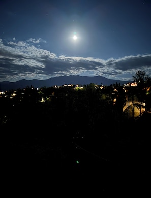 A night view of a town with a prominent mountain in the background and a bright moon in the sky. - Luxury 3-story cabin! MTN Views Hot Tub, Game Room, Fire Pit, Book Fall Now! (Gatlinburg)