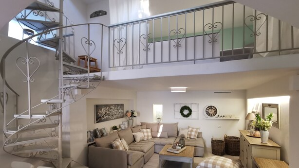 Amplia sala de estar con una escalera en espiral, un conjunto de sofás, una mesa de centro y una mesita auxiliar.