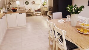 Cucina spaziosa con mobili bianchi, un tavolo da pranzo in legno e un frigorifero nero.