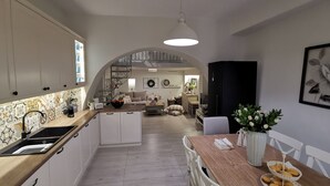 Una cucina moderna con isola centrale, mobili bianchi e zona pranzo con tavolo e sedie in legno.
