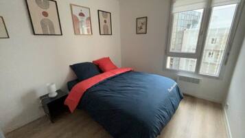 Un dormitorio con cama, mesita de noche, ventana y decoración en la pared.