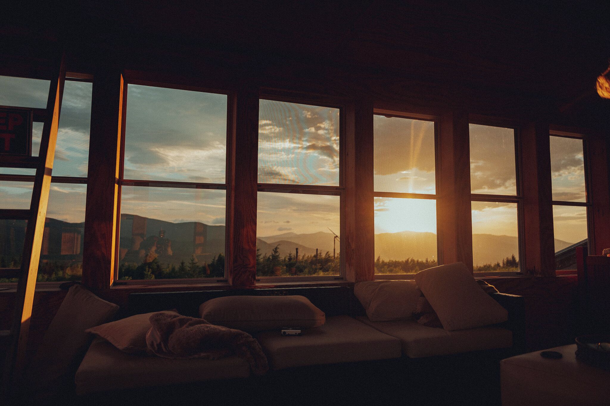 A room with a large window overlooking a landscape, a sofa, and a television.