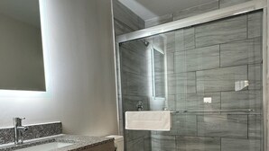 Un baño moderno con ducha de vidrio, tocador con lavabo y retrete.