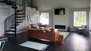 A modern living room with a spiral staircase, a fireplace, and large windows.